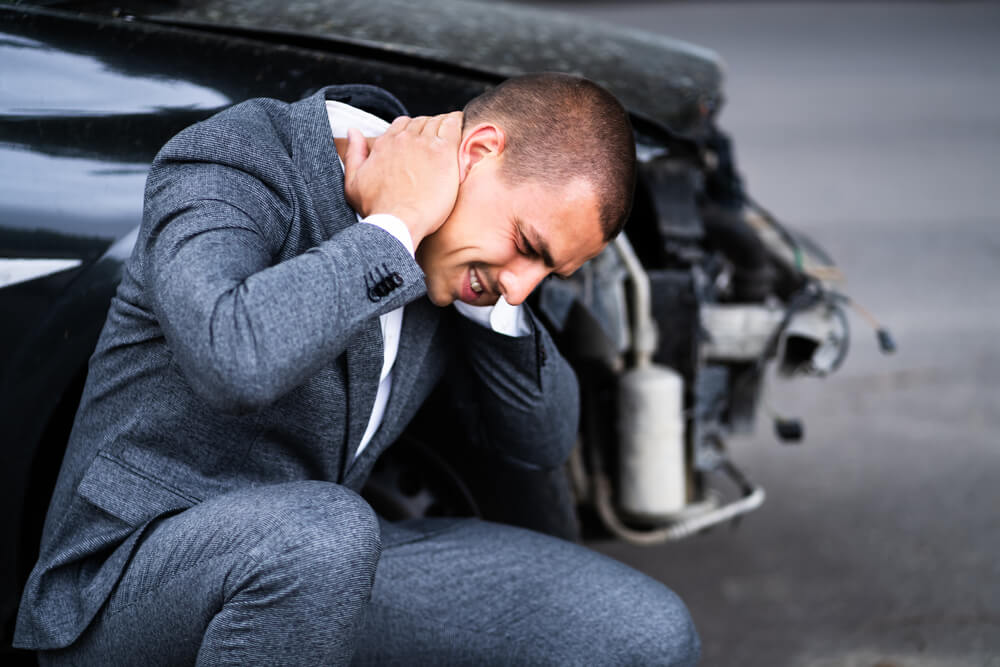 a man sitting near to his car after an accident.